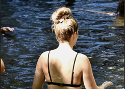 Woman wading through lake near waterfall